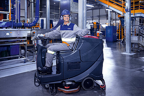 Leadec employee driving cleaning machine on shopfloor of Food & Beverage factory.