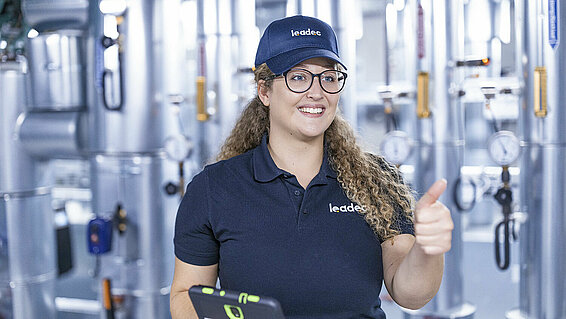 Female Leadec in a technical room employee hold thumbs up.