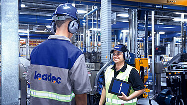 Two Leadec employees with tablet showing Leadec.os in a factory.